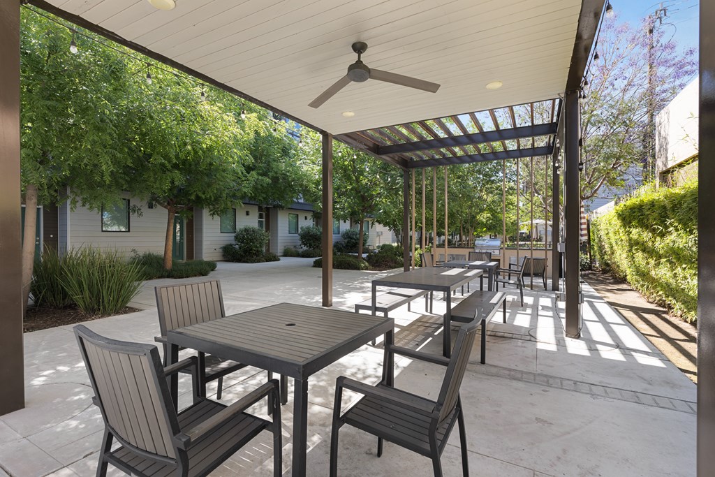A patio with a table and chairs under a roof.